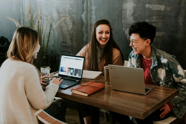 The image of a three people sitted around a table , discussing.